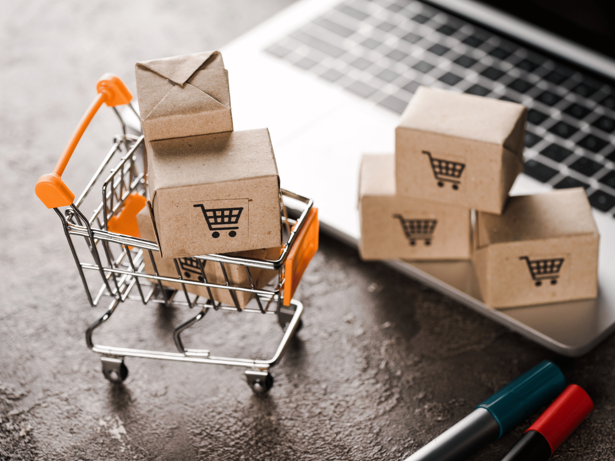 E-Commerce-Erfolg mit Shopify Agentur: Einkaufswagen, Pakete mit Einkaufswagen-Symbolen und Laptop.